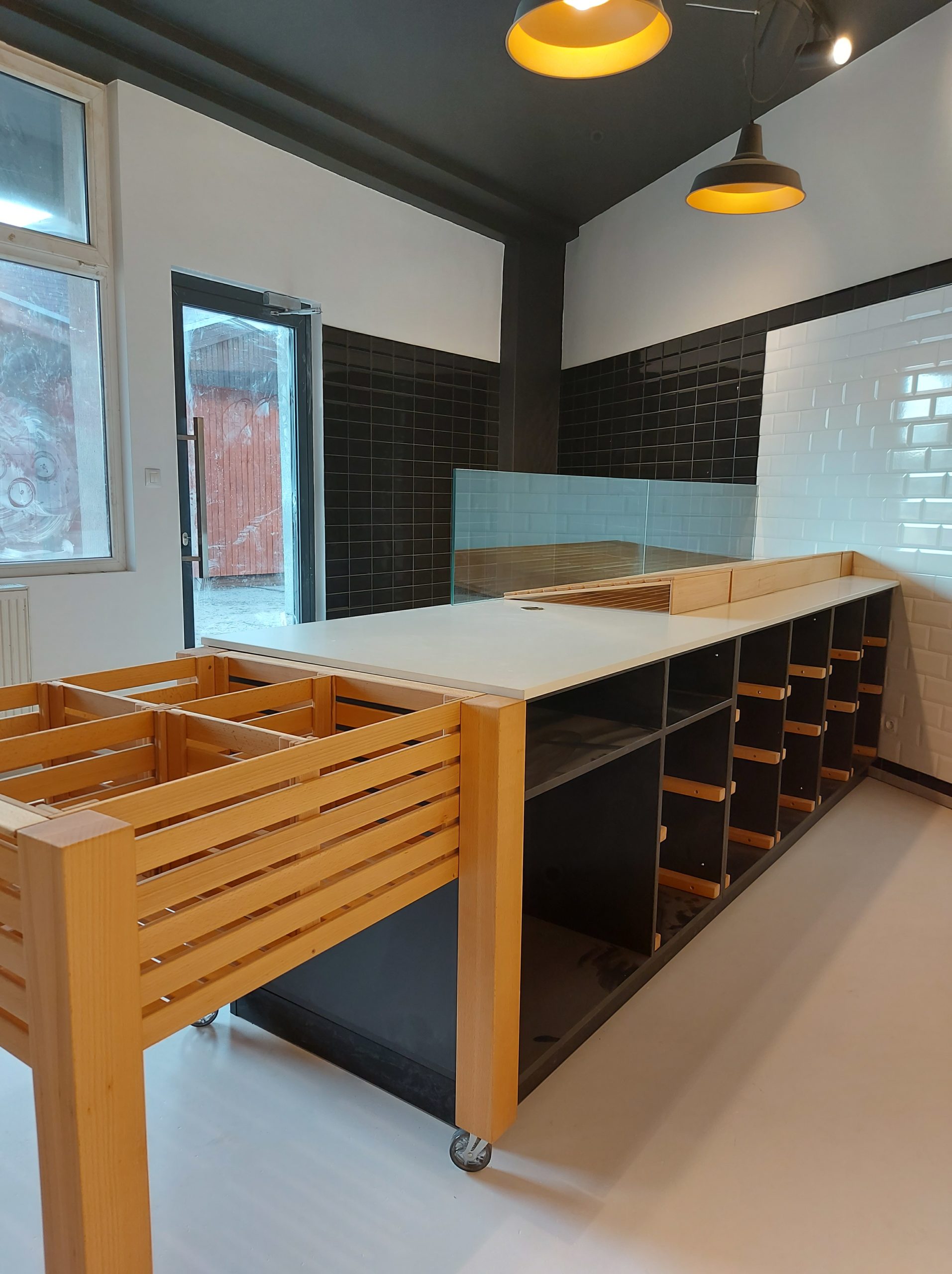 moderný interiér predajne, drevený predajný pult, biele obkladačky metro, industriálne svietidlá, dizajn obchodu