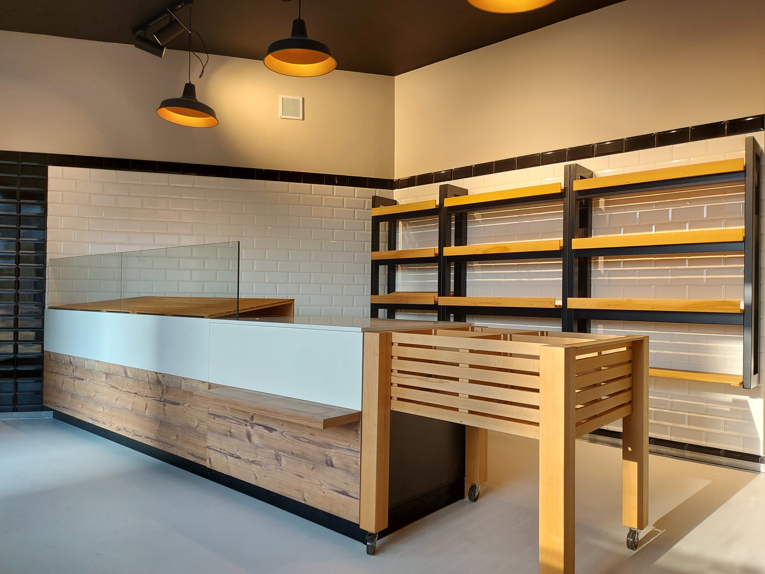 moderný interiér predajne, drevený predajný pult, biele obkladačky metro, industriálne svietidlá, dizajn obchodu